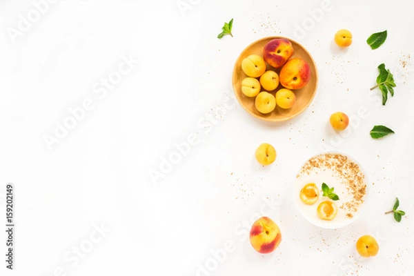 Fototapeta Fresh summer fruit. Healthy breakfast with peach, nectarine, apricot, muesli, peach yogurt, mint, cereal on white background. Flat lay, top wiew.