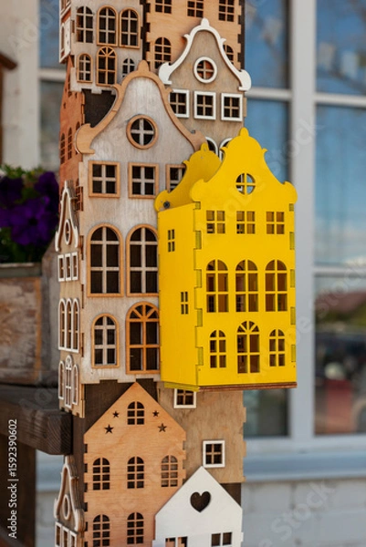 Fototapeta Decorative plywood houses are attached to a post, forming a whimsical and creative display