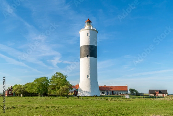 Fototapeta The tall lighthouse Long Jan on the island Oland in Sweden, seen with surrounding landscape and buildings on a fine sunny evening.