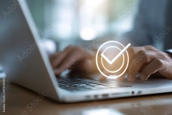 Fototapeta Hands typing on a laptop with a glowing check mark overlaying the keyboard close up and blurry background