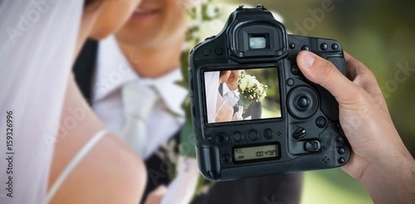 Obraz Złożony obraz przyciętej ręki fotografa trzymającego aparat