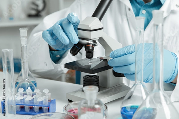 Fototapeta men in a laboratory microscope with microscope slide in hand