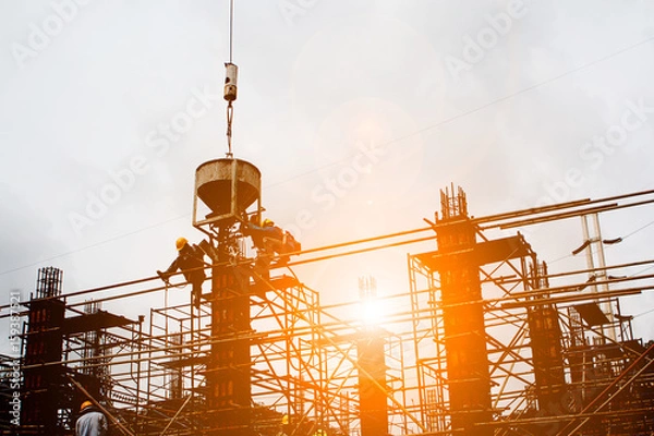 Obraz Silhouette construction industry team safely to work load concrete building according to set goal over blurred background sunset pastel for industry background.