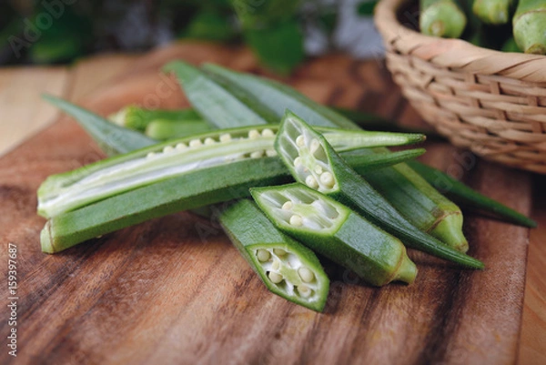 Obraz whole and portion cut fresh okra on cutting board