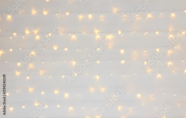 Fototapeta Soft warm white string lights on neutral background creating cozy atmosphere.