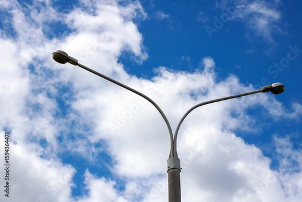 Fototapeta A street light stands tall against a cloudy blue sky during evening