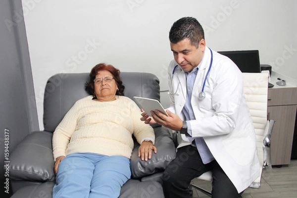 Fototapeta An elderly Latina woman in consultation with a geriatric specialist for a checkup notes her symptoms with the office