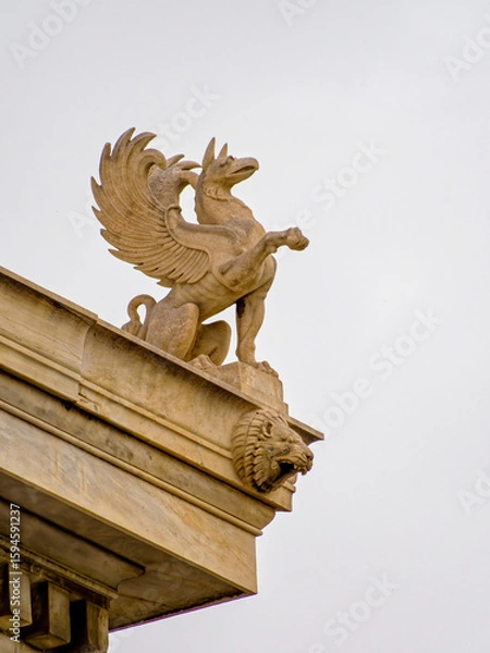 Fototapeta Majestic griffin sculpture on the National Academy of Greece in Athens, embodying ancient myths. Space for your text and logo.