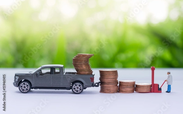 Fototapeta Miniature truck carrying stack of coins, worker loading stack of coins using as a business concept.
