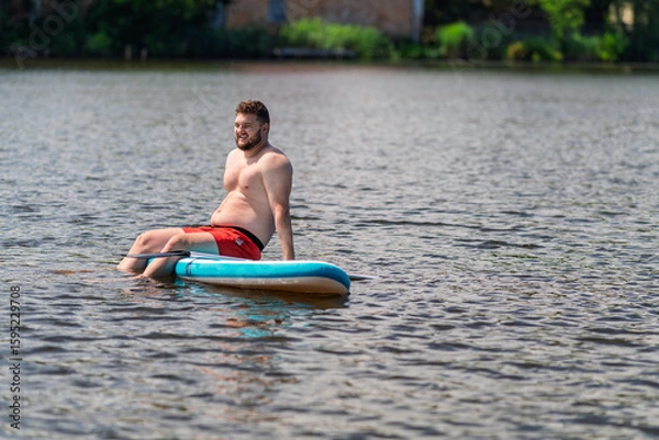 Fototapeta A man was on a SUP board in the middle of a lake and was enjoying himself.