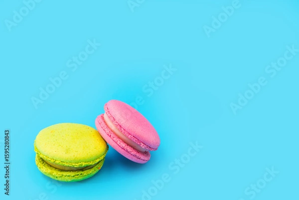 Obraz Mixed of colorful macaroni or pasta cake on a blue background. Sweet and colorful french macarons. Two multi-colored green and pink macaroons. Culinary and cooking concept, styling food.