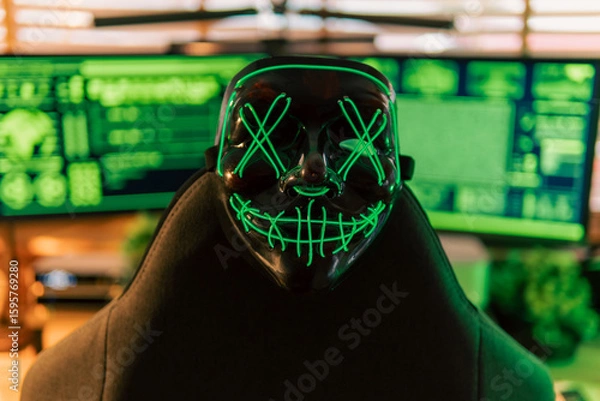 Fototapeta In a dimly lit cyber lair, a glowing hacker mask watches over a desk as encrypted code streams across three glowing monitors — the hack has already begun.