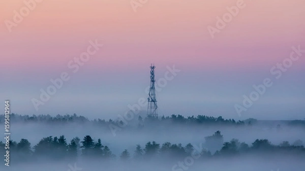Obraz Cell tower emerging from fog at dawn