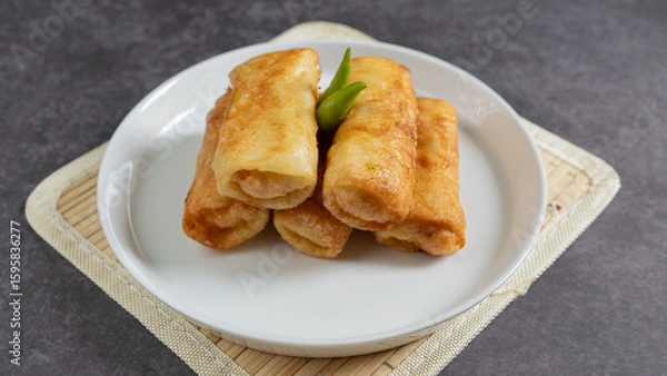 Obraz Sosis Solo (Sausage Solo). Special designation for a chicken dish wrapped in an omelet and shape like sausagea. Traditional Indonesian meat snack, served on a white plate with green chili garnish.