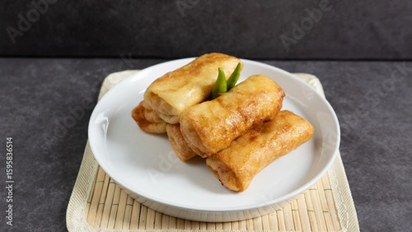 Obraz Sosis Solo (Sausage Solo). Special designation for a chicken dish wrapped in an omelet and shape like sausagea. Traditional Indonesian meat snack, served on a white plate with green chili garnish.