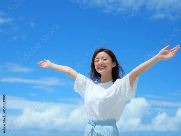 Fototapeta 青空の下で両手を広げて笑顔を見せる日本人女性