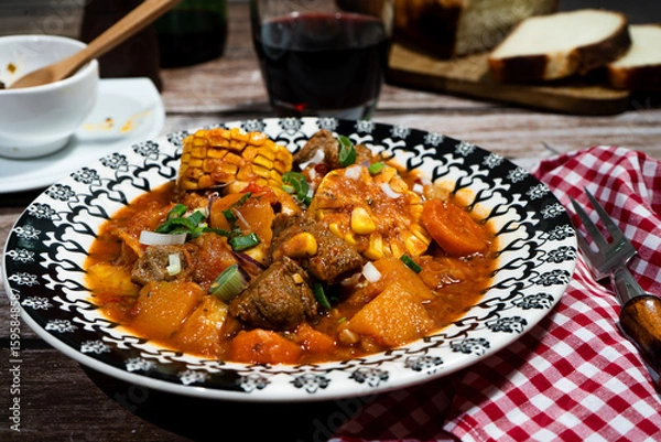 Fototapeta Delicious beef stew called carbonada with corn on the cob, vegetables, and red wine