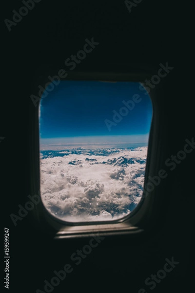 Fototapeta Clouds and sky as seen through window of an aircraft