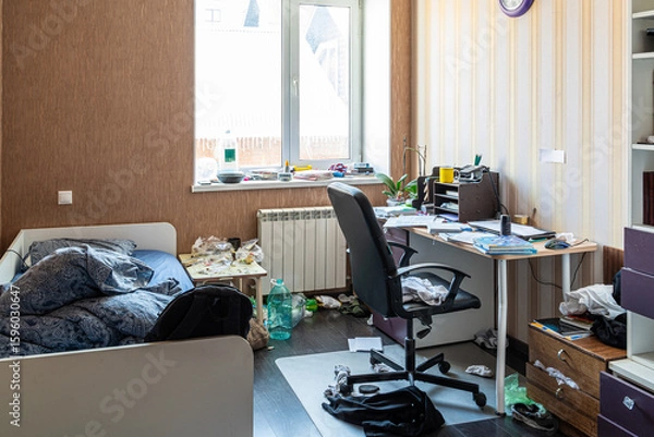 Fototapeta Clutter mess trash and dirt in a 15-16 year old teenage boy's room with scattered belongings, laundry and textbooks, untidy bed