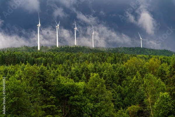 Fototapeta Wind turbines in the clouds over a mountain