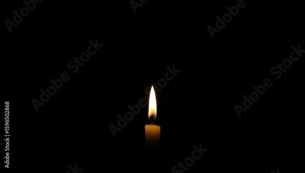 Fototapeta A single candle flame burning brightly in the darkness creating a warm and inviting glow in the night