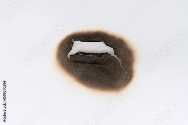 Fototapeta Burnt hole isolated on white paper. burns borders paper close up. Paper burn black stain mark close up.