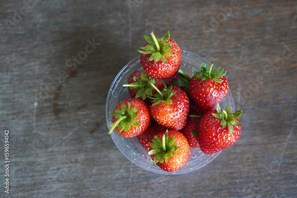 Fototapeta  top view many fresh strawberries in a clear plastic glass lid on a wooden table background, fruit, food, decor, object, copy space