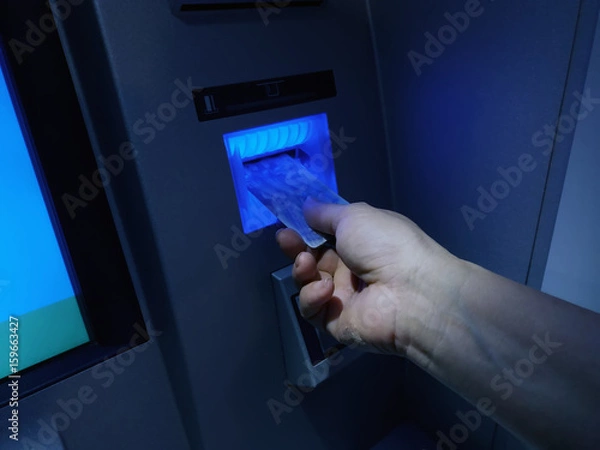 Fototapeta Hand inserting ATM card into bank machine to withdraw money