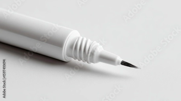 Fototapeta Close-up shot of a white eyeliner pen with a fine black tip, resting on a white surface.