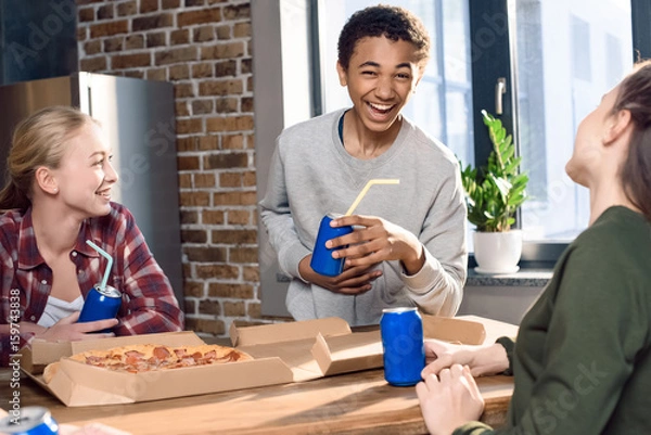 Fototapeta happy friends spending time together with pizza and soda drinks, eating pizza at home concept