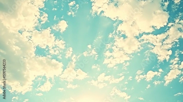 Fototapeta Light pastel-toned sky, filled with fluffy clouds