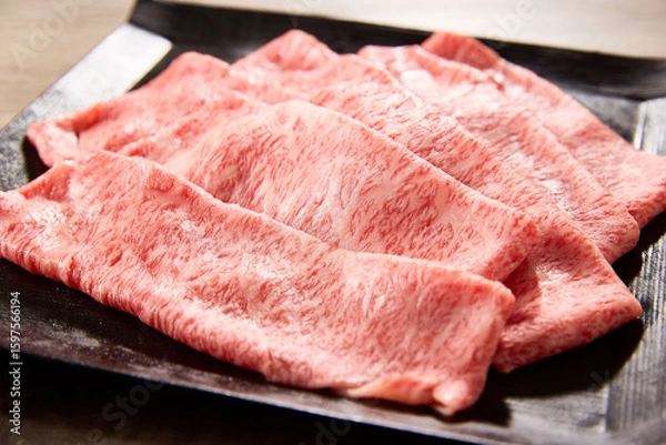 Obraz 黒毛和牛の霜降りスライス肉を黒い角皿に美しく盛り付けたクローズアップ写真。艶やかな脂と繊細なサシ模様が際立つ高級食材のイメージカット。焼肉やすき焼きに最適。
