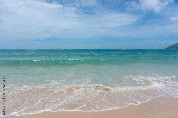 Fototapeta Seascape on waves with foam and spray, sky and beach. Ocean waves crashing on a sandy beach
