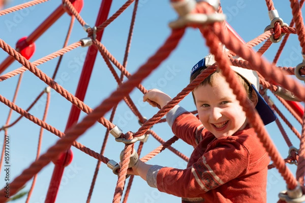 Obraz Young boy child playing at outdoor playground climbing net