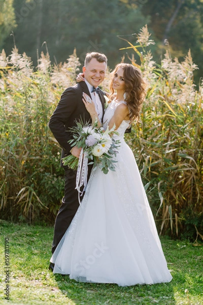 Fototapeta Portrait of the bride and groom in full growth at a wedding on nature in the spring at sunset