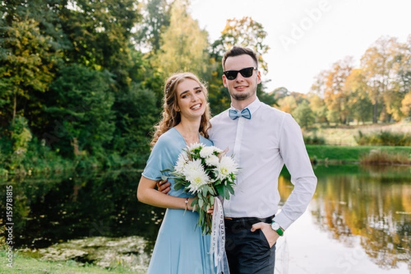 Fototapeta A nice, warm portrait of a stylish bridegroom and a charming bride in the nature