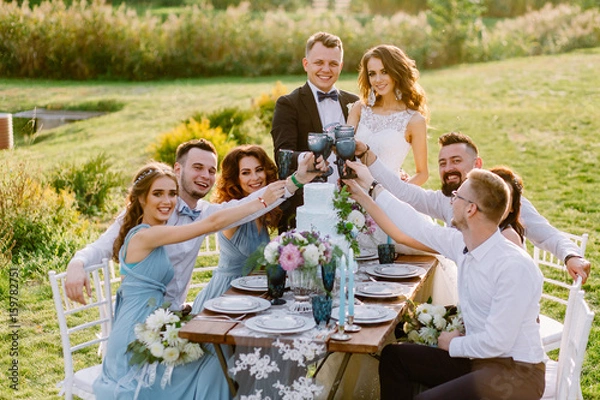 Fototapeta Positive guests celebrate at the table the wedding of their friends in the nature