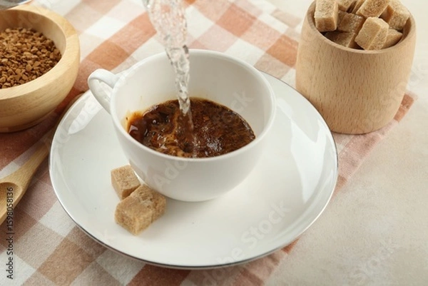 Fototapeta Pouring hot water into cup with instant coffee at light table, closeup