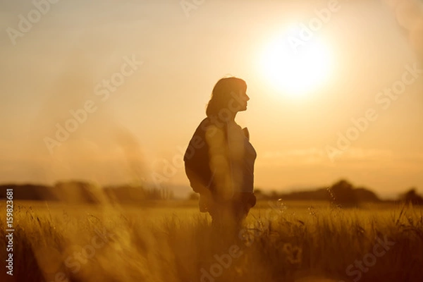Fototapeta Middle aged caucasian woman standing in the sunlit field with open arms, embracing nature