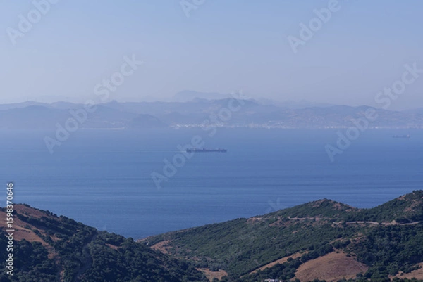 Obraz Cargo vessel navigating narrow gibraltar strait, connecting european and african coastlines, symbolizing international maritime commerce