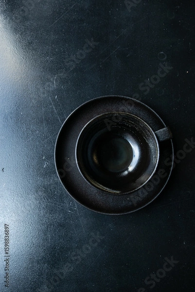 Fototapeta an empty black cup stands on a saucer with crumbs on a black windowsill