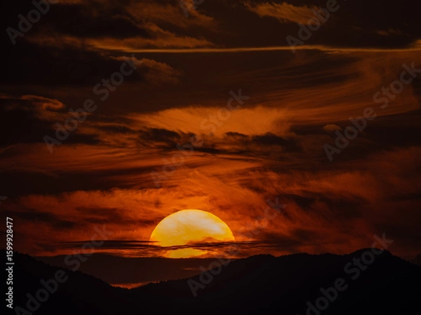 Obraz 荒れた天気で雲が渦巻く中に沈む夕陽