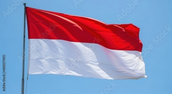 Obraz The national flag of Indonesia, Sang Saka Merah Putih, waving powerfully in the wind on a tall flagpole.