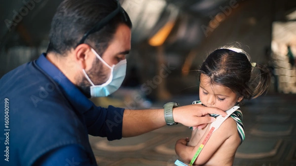 Fototapeta A doctor examines children's malnutrition inside a refugee camp. Malnutrition was measured using a mid-upper arm circumference belt.