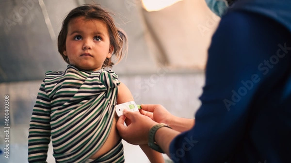 Fototapeta A doctor examines children's malnutrition inside a refugee camp. Malnutrition was measured using a mid-upper arm circumference belt.