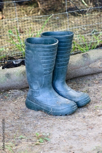Obraz Czrane kalosze w ogrodzie. Buty gumowe do pracy w polu i na działce. Obuwie robocze