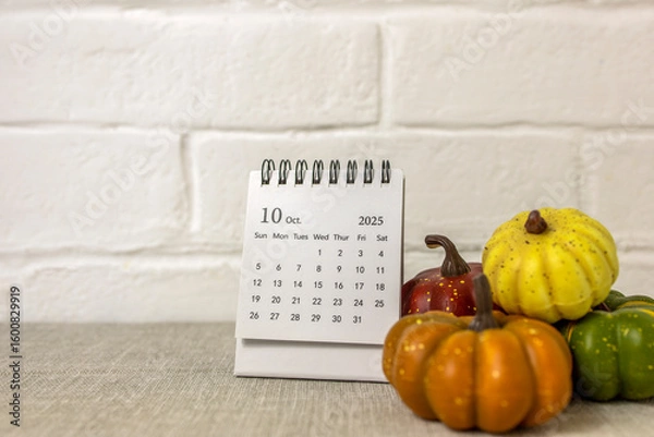 Fototapeta A desktop calendar for October 2025 and a pumpkin on the table. Halloween is coming soon.