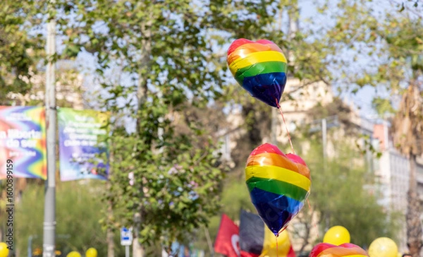 Obraz Heart-shaped balloons in rainbow colors create a festive atmosphere as people gather to celebrate Pride in Barcelona. The event showcases love, acceptance, and colorful decorations on a summer day.