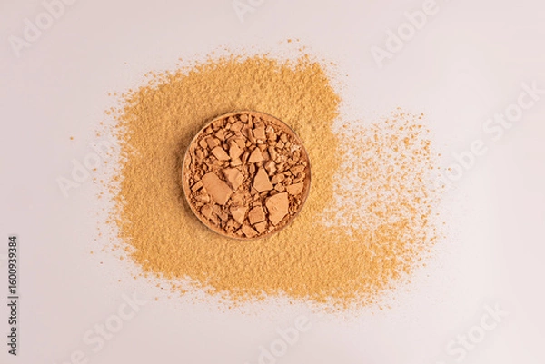 Obraz A block of compact powder, broken into pieces, stands on loose dry powder in a beige tone. A copy of the space. top view. Product layout.