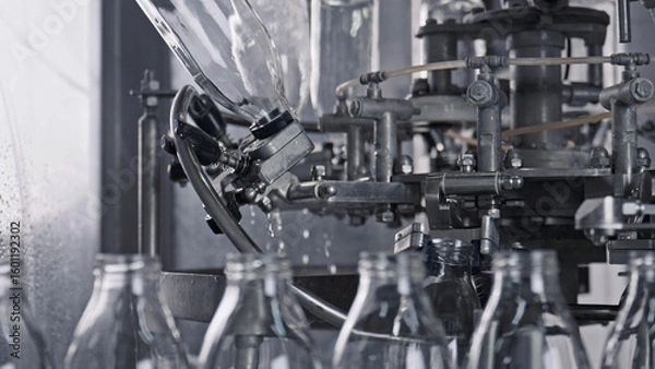 Fototapeta Industrial bottling machine pouring milk into